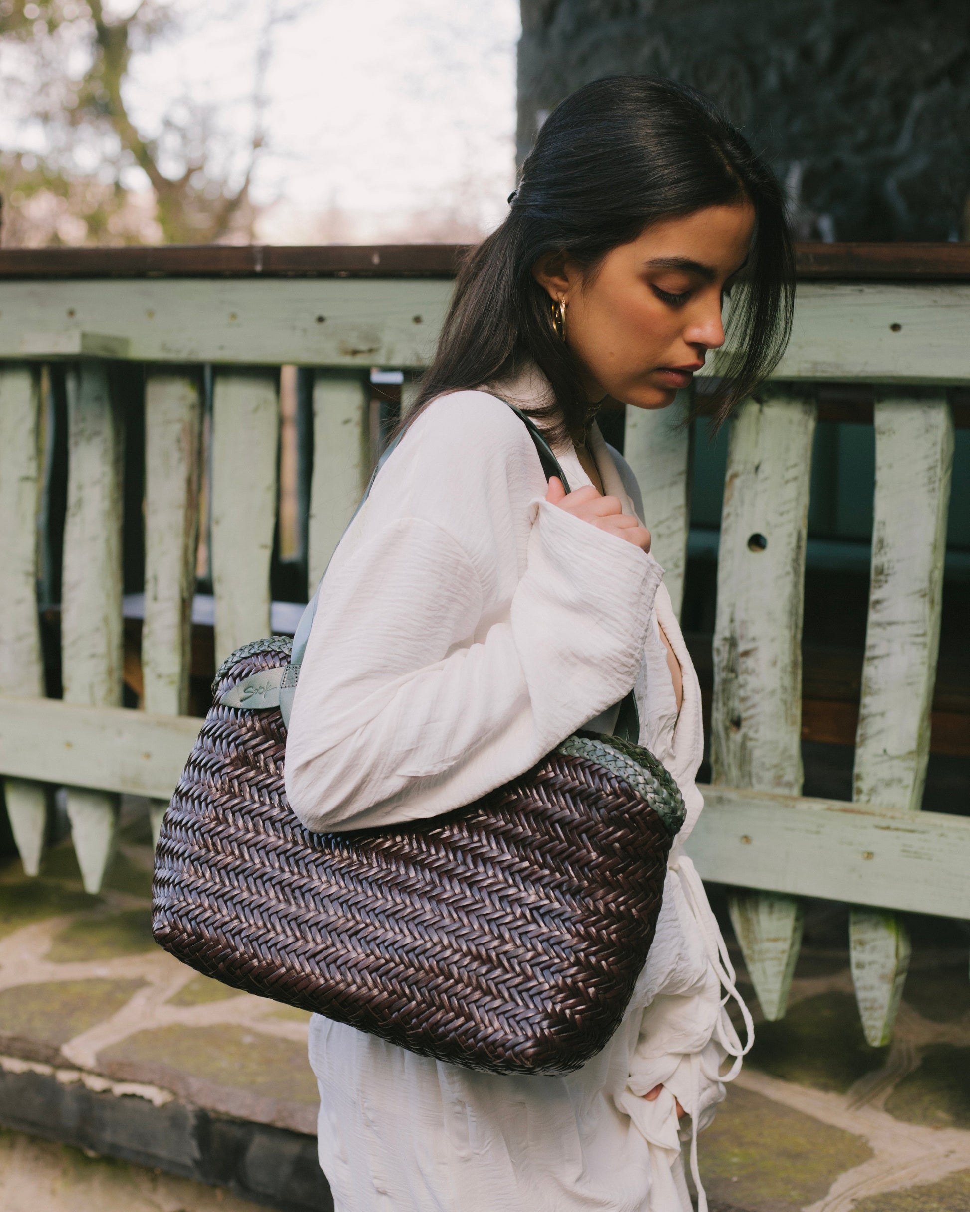 Léafa - Handwoven Leather Shoulder Bag | Green & Coffee carried with visible woven leather texture and dark coffee base in natural outdoor setting.