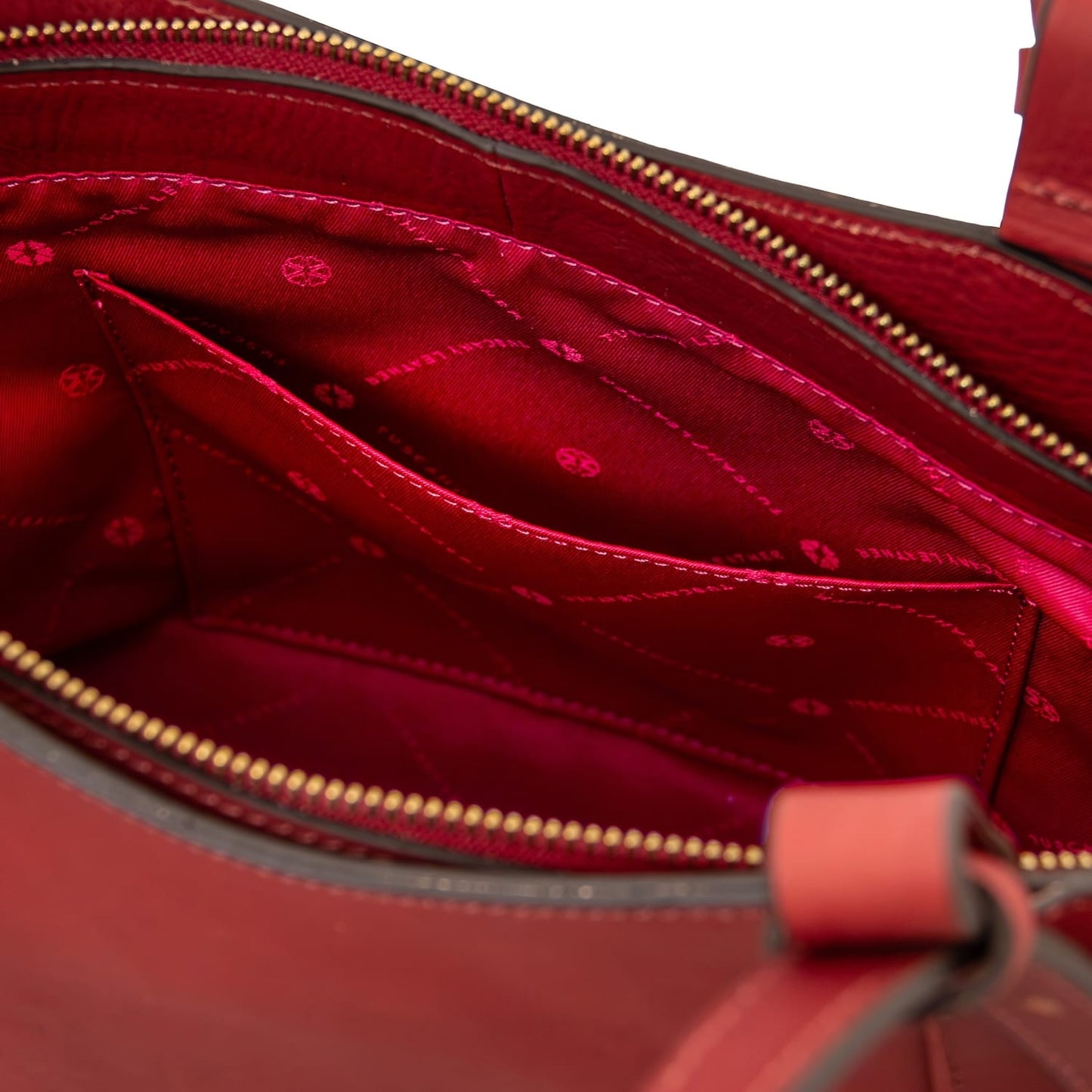 Inside view of a brown leather tote with red lining and stitched pockets.