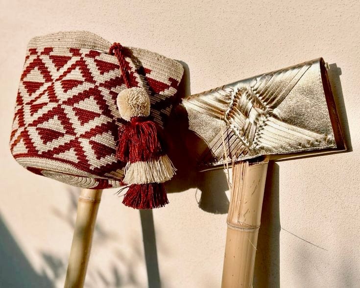 LUEE Mochila Bag with a red geometric pattern and white tassels hanging on a beige wall background