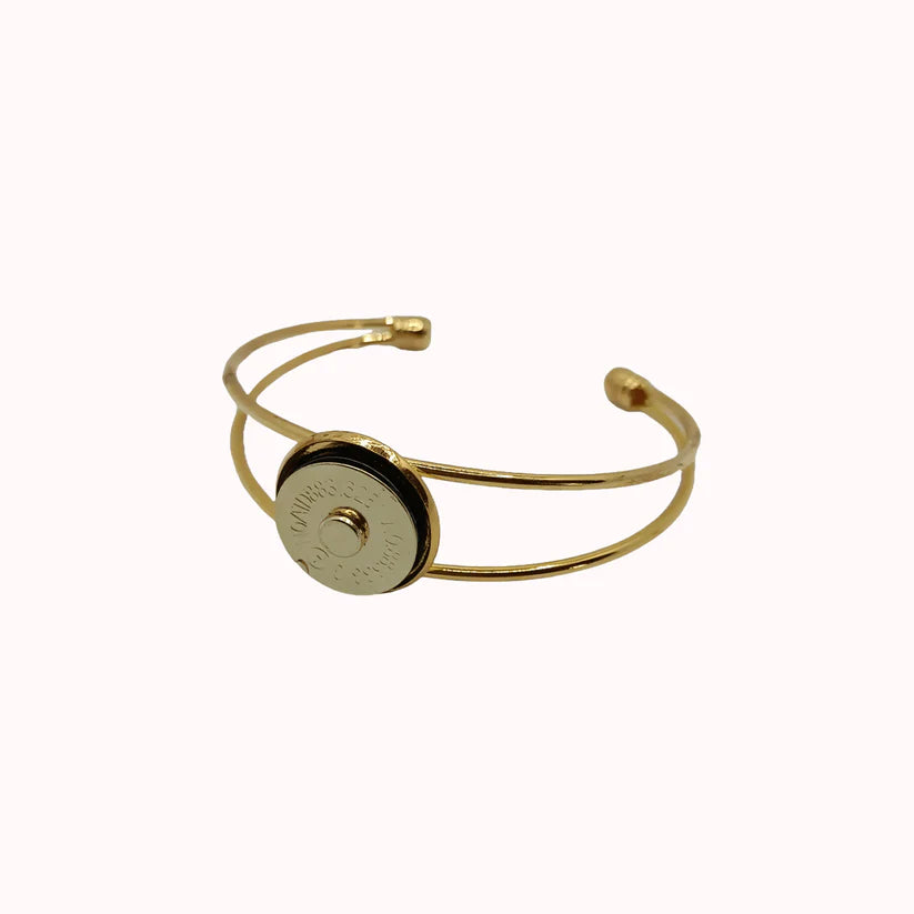 Gold bracelet with a circular black and gold component on a white background