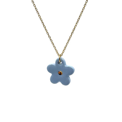 Blue flower ceramic pendant on a gold chain against a white background