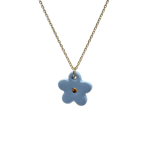 Blue flower ceramic pendant on a gold chain against a white background