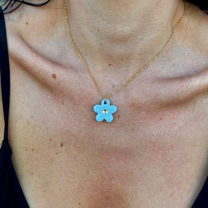 Light blue flower ceramic pendant with a gold center on a gold chain