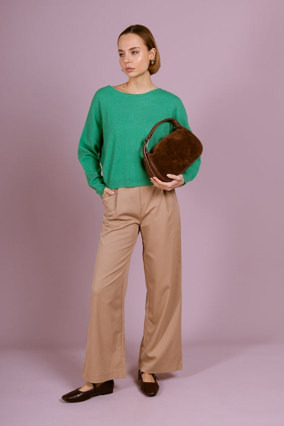 Person wearing green sweater and beige pants holding Montepulciano – Italian Suede Leather Hobo Bag in brown suede with leather strap.