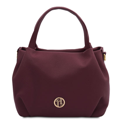 Nora - Soft leather handbag | TL142372 in burgundy pebbled leather with dual top handles and gold-tone round emblem on white background