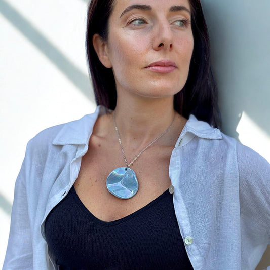 Close up of model wearing Perla light blue ceramic pendant necklace with silver chain