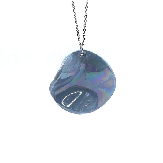 Iridescent blue ceramic pendant necklace on a silver chain against a white background