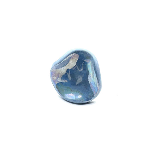 Close-up of a single light blue pearl ceramic ring with an irregular rounded shape on a white surface.
