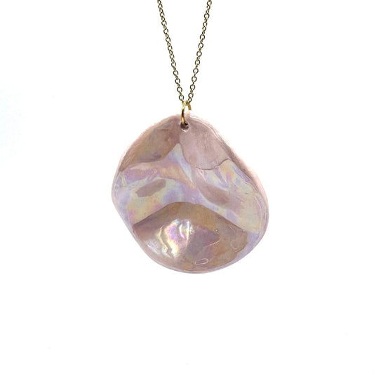 Pearl-pink ceramic pendant necklace on a gold chain against a white background