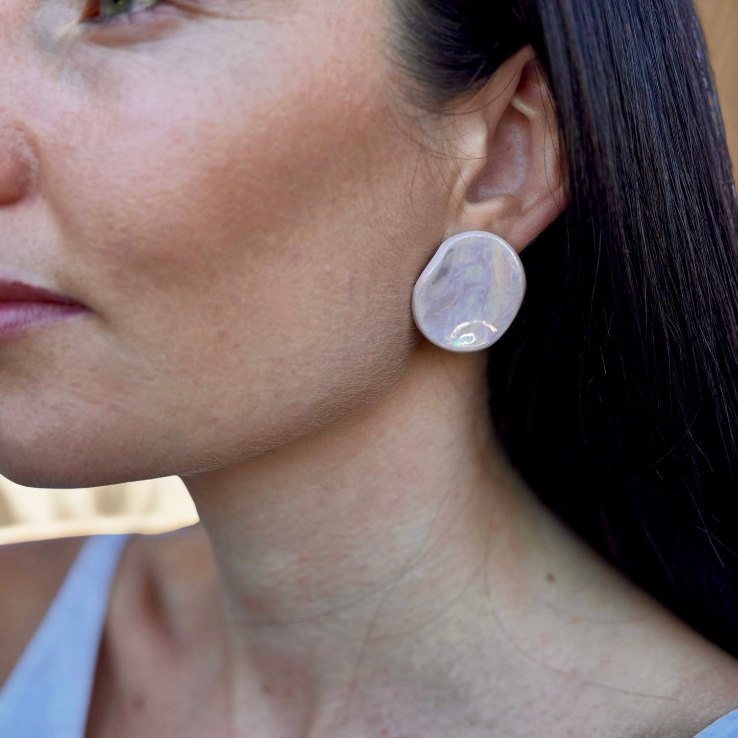 Close-up of a pearl pink ceramic stud earring worn on the ear