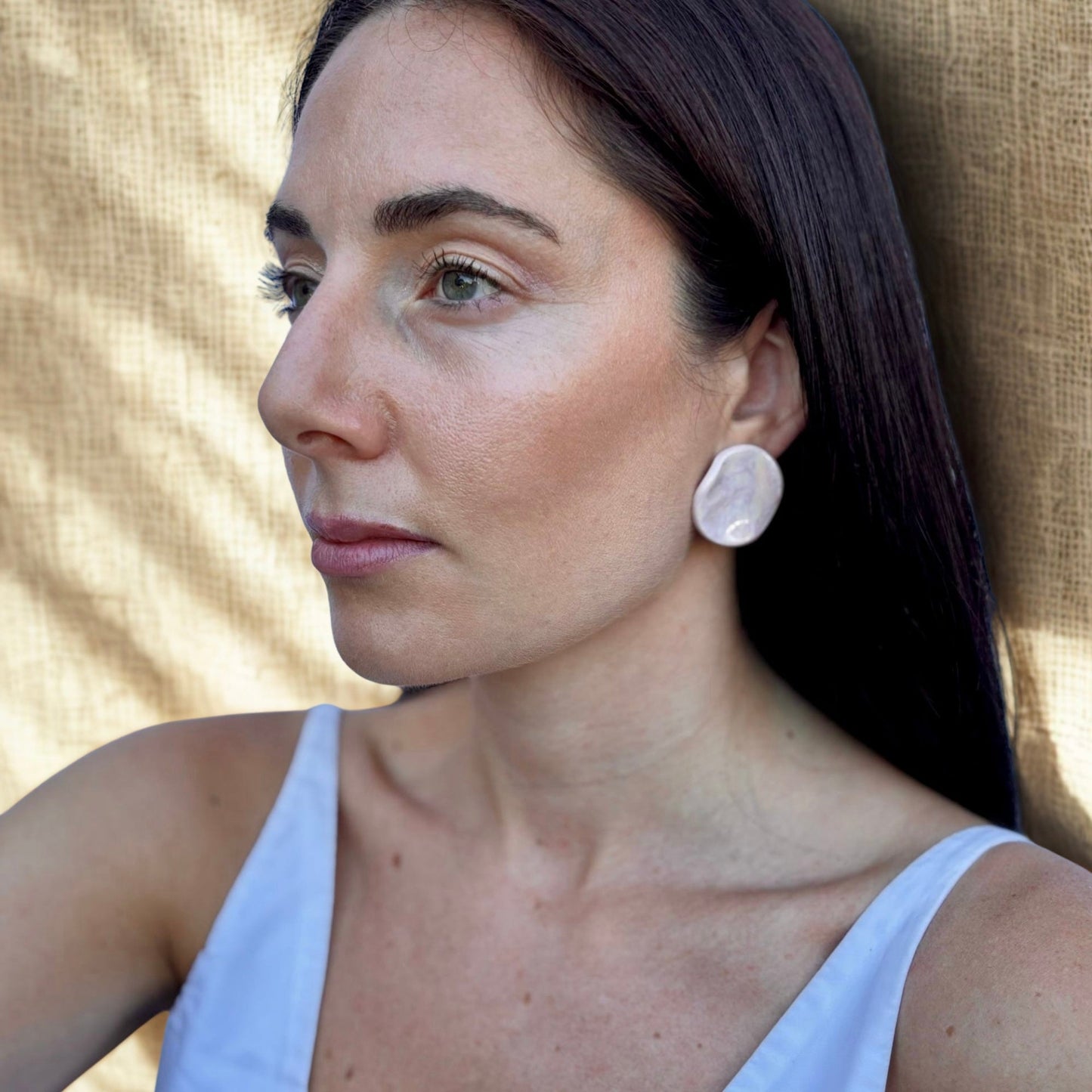 Side profile of a woman wearing a round pearl pink ceramic stud earring
