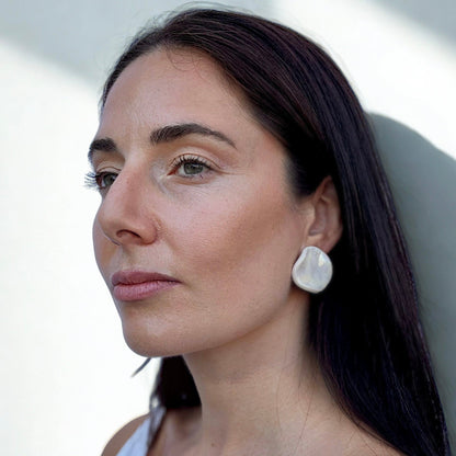 Model wearing a large pearl white ceramic earring on her ear