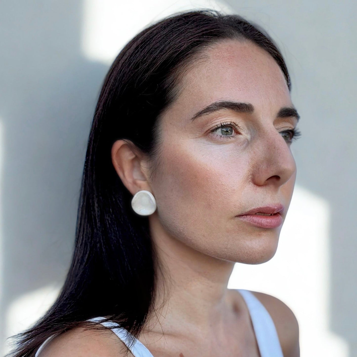 Side view of a woman wearing a pearl white ceramic stud earring