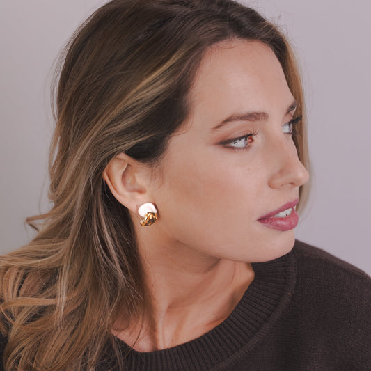 Close-up of a woman wearing Petali white ceramic stud earrings with gold luster