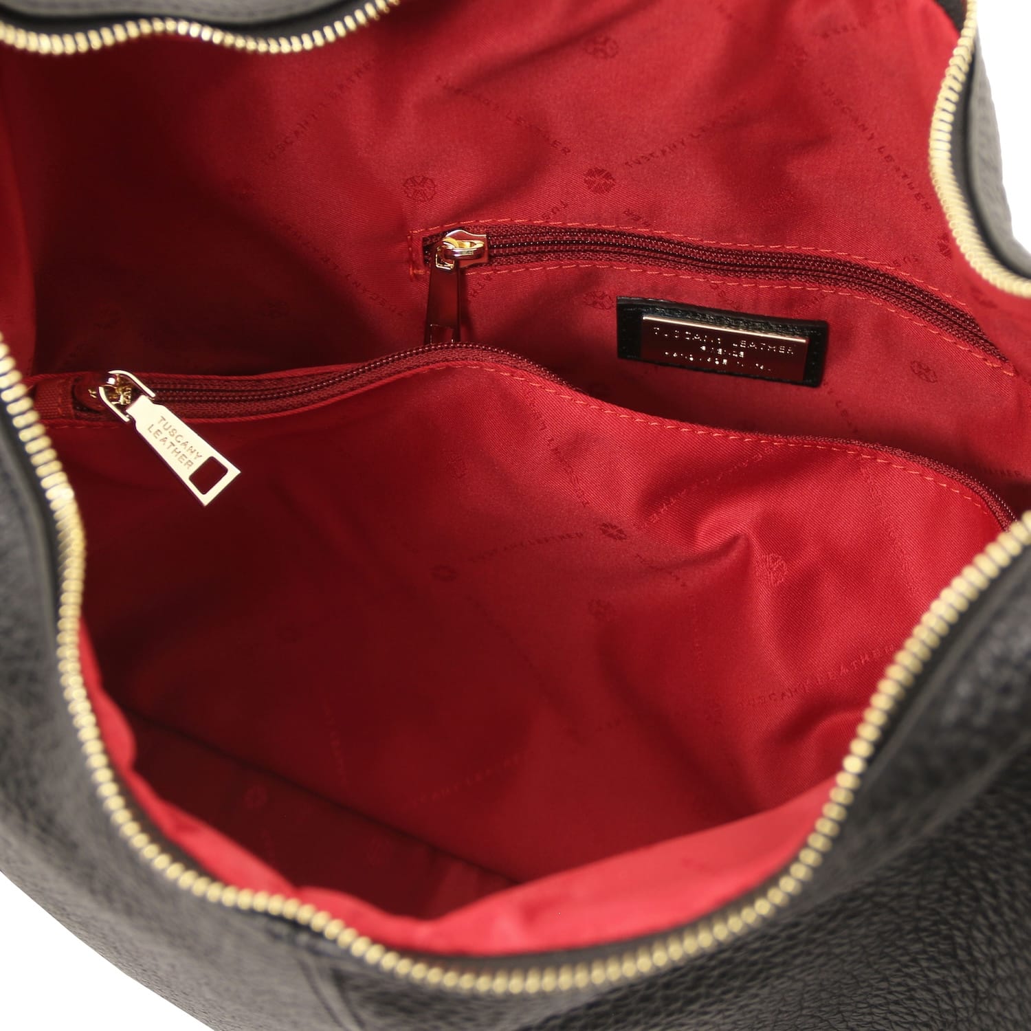 Red interior lining with zip pocket and brand plaque inside a black leather handbag