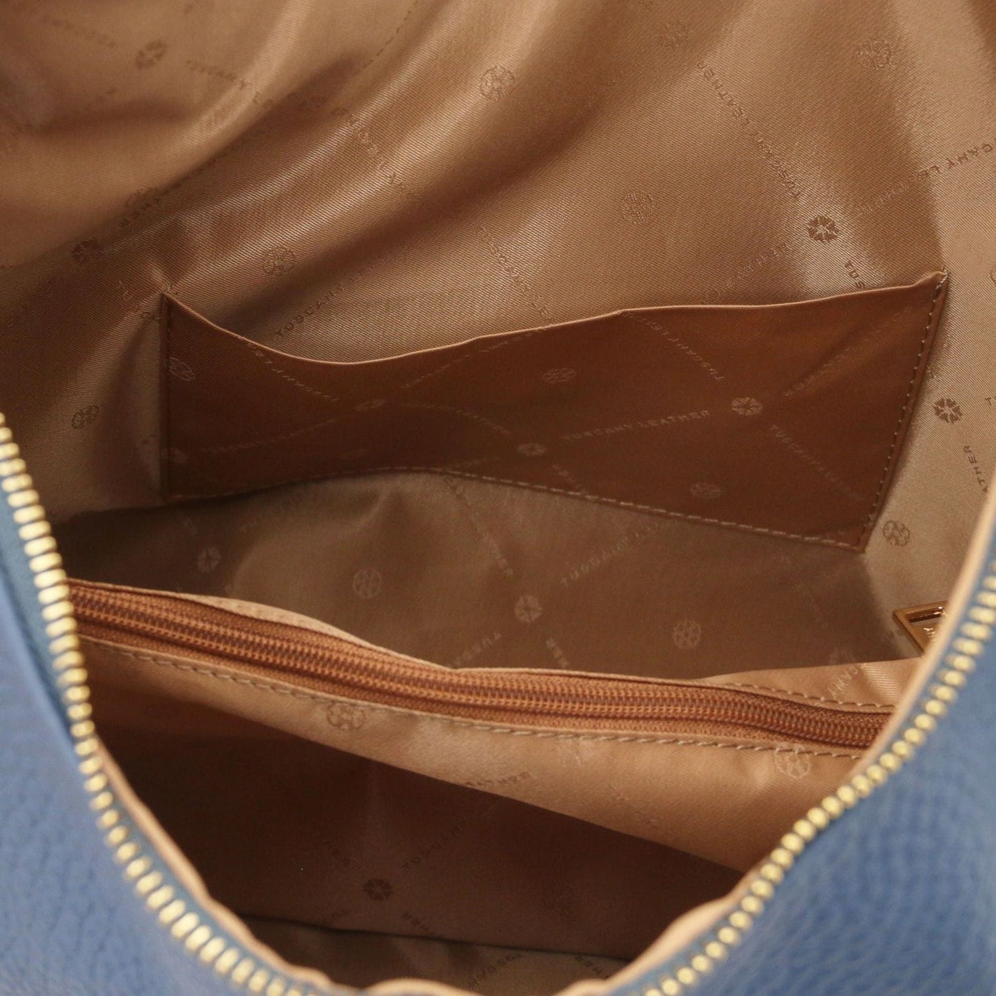 Tan interior with curved brown slip pocket and logo patterned lining inside the bag