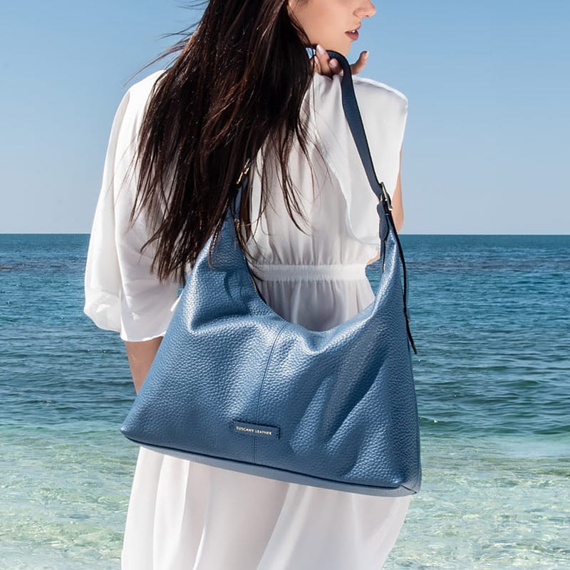 Woman holding a blue bag by the ocean