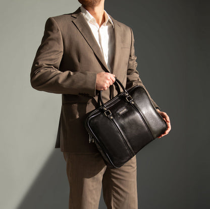 Man holding a black leather briefcase against a gray background