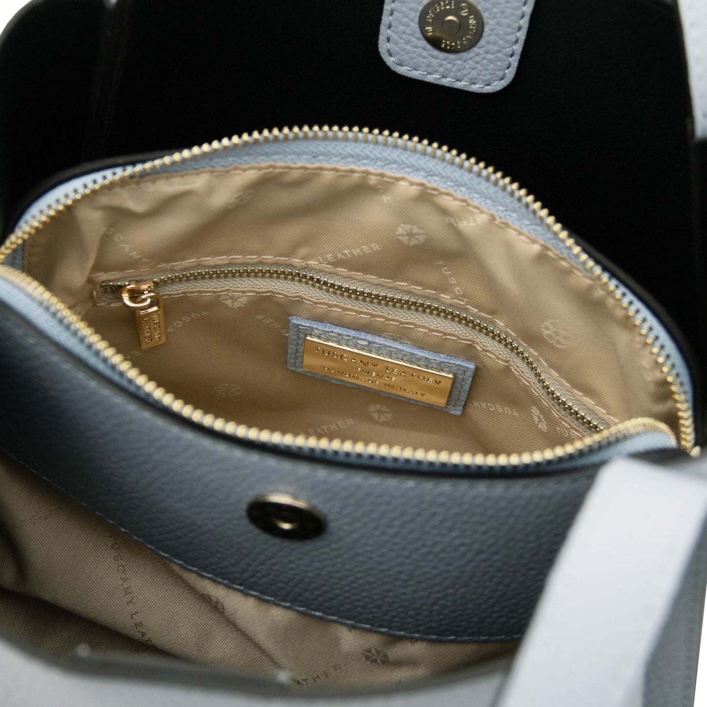 Inside view of the Soave handbag with beige lining, zip pocket and a gold label plaque.