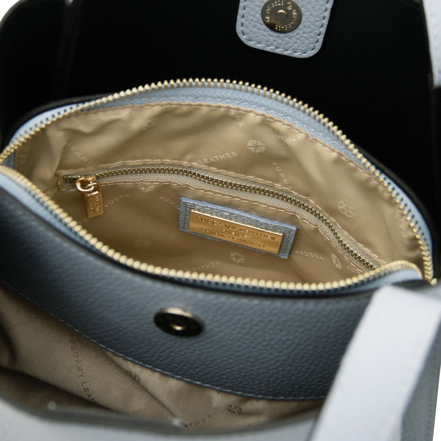 Inside view of the Soave handbag with beige lining, zip pocket and a gold label plaque.
