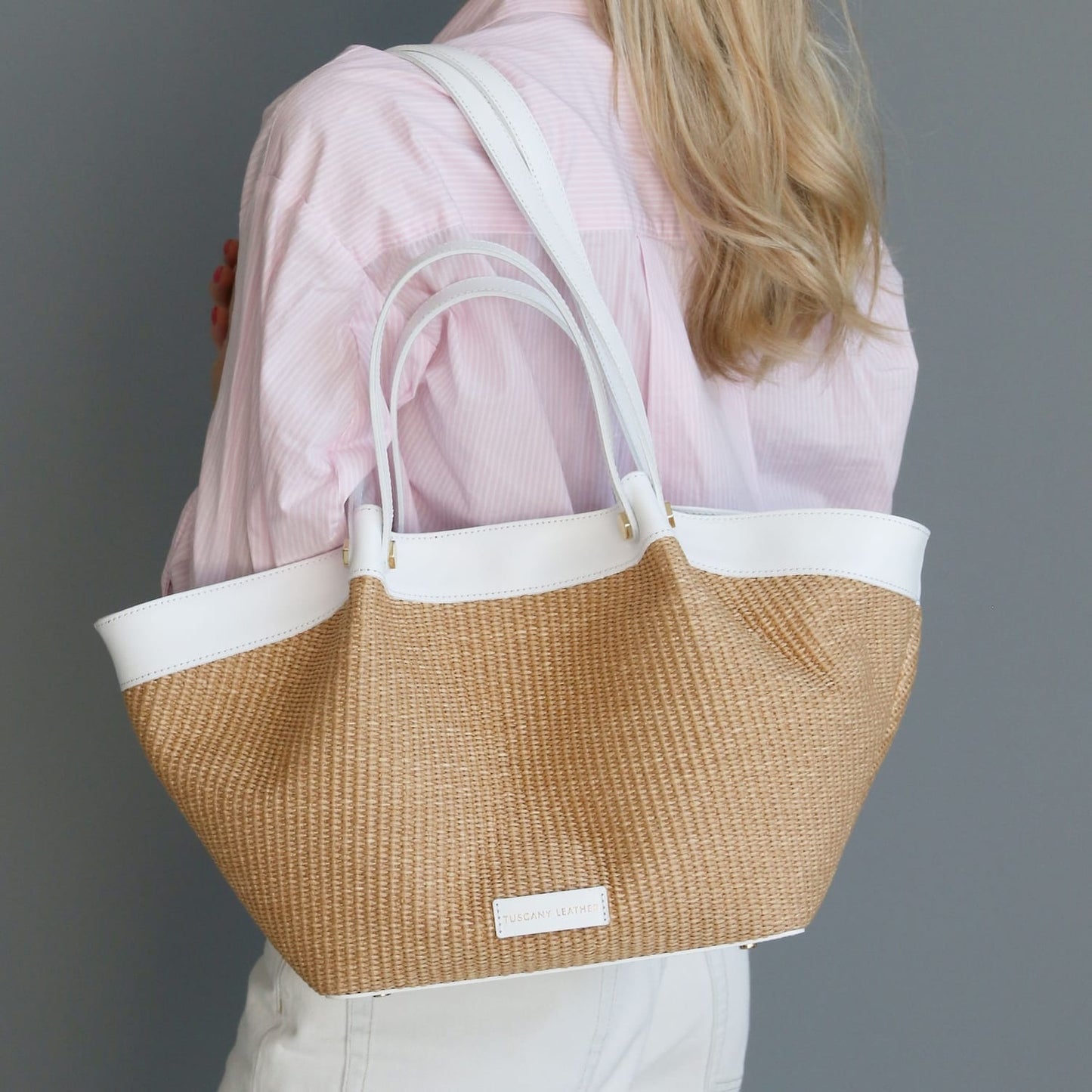 Soleil raffia shopping bag with white leather trim and white handles carried by a model