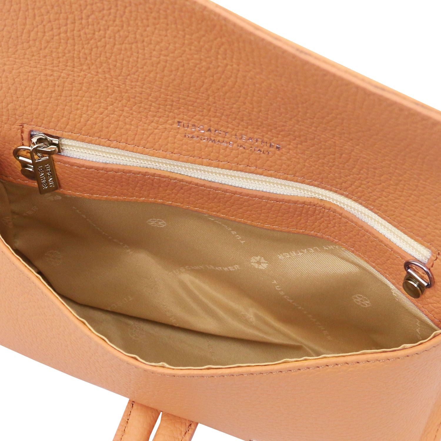Interior of tan pebbled leather foldover clutch with zip pocket and beige lining.