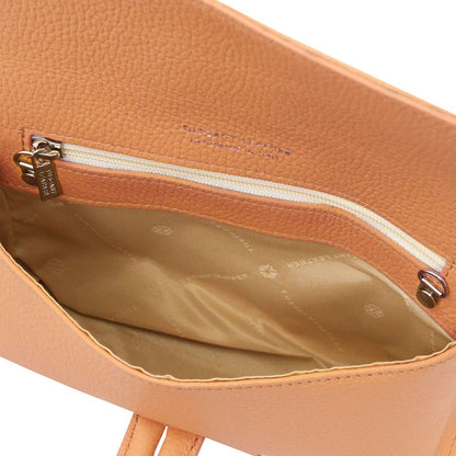 Interior of tan pebbled leather foldover clutch with zip pocket and beige lining.