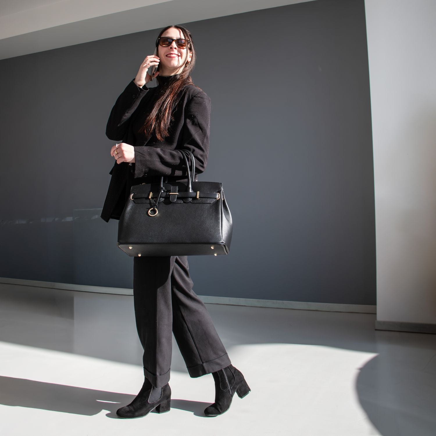 TL Bag leather handbag with gold hardware carried by a woman in a black outfit.
