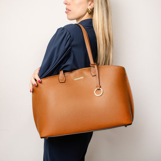 Model carrying a large tan pebbled leather shopping bag with top handles