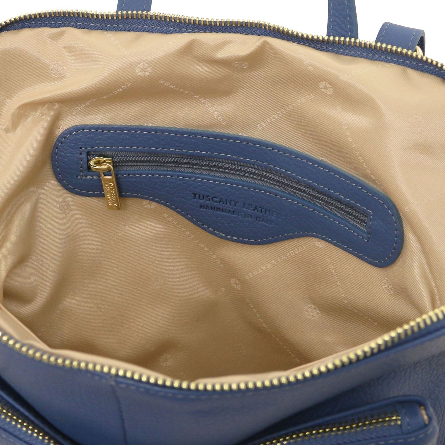 Interior of blue bag with beige lining and a zip pocket.