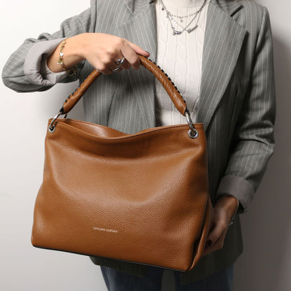 Tan TL Bag in pebbled leather held by a person wearing a gray pinstripe blazer
