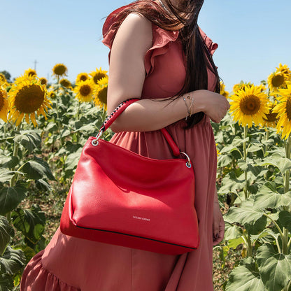 Model in a pink dress carries a red TL Bag through a sunflower field