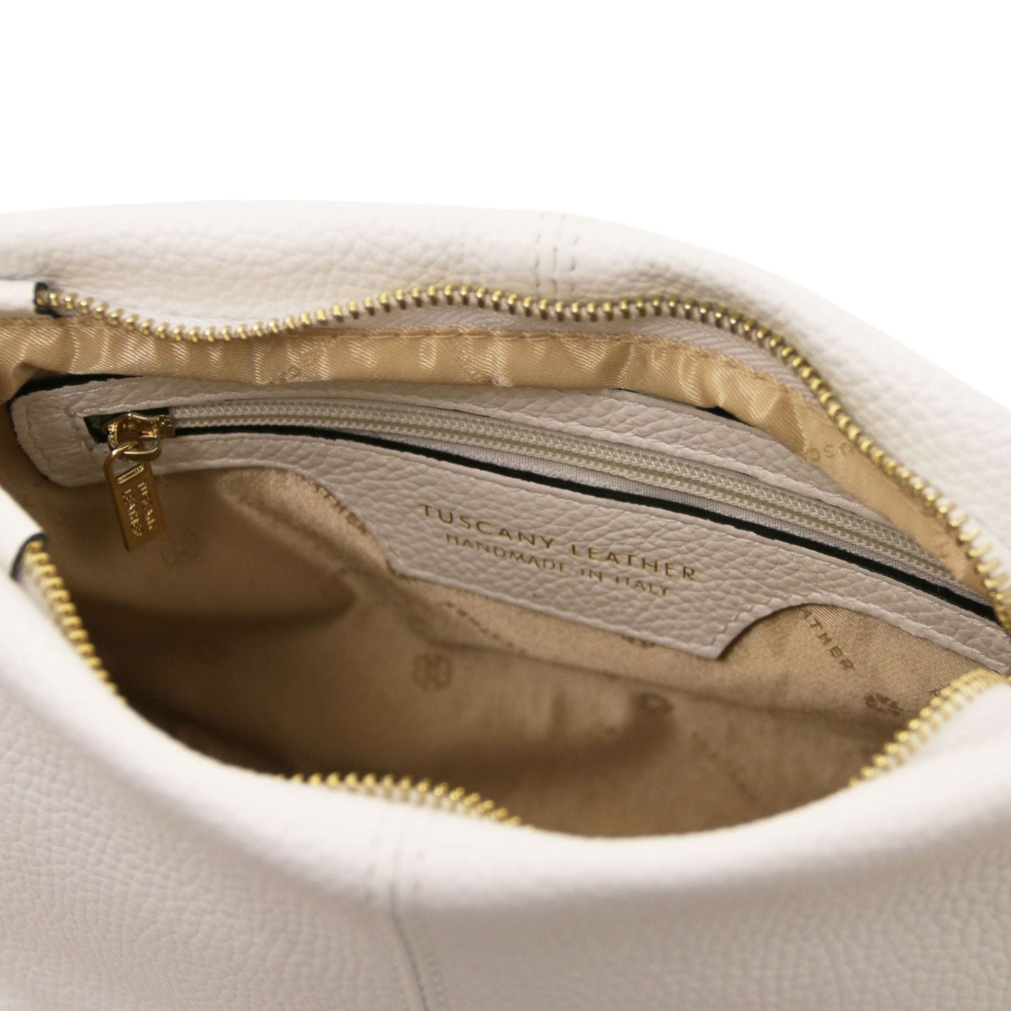 Interior view of soft white leather shoulder bag showing gold zipper and beige fabric lining with Tuscany Leather label.