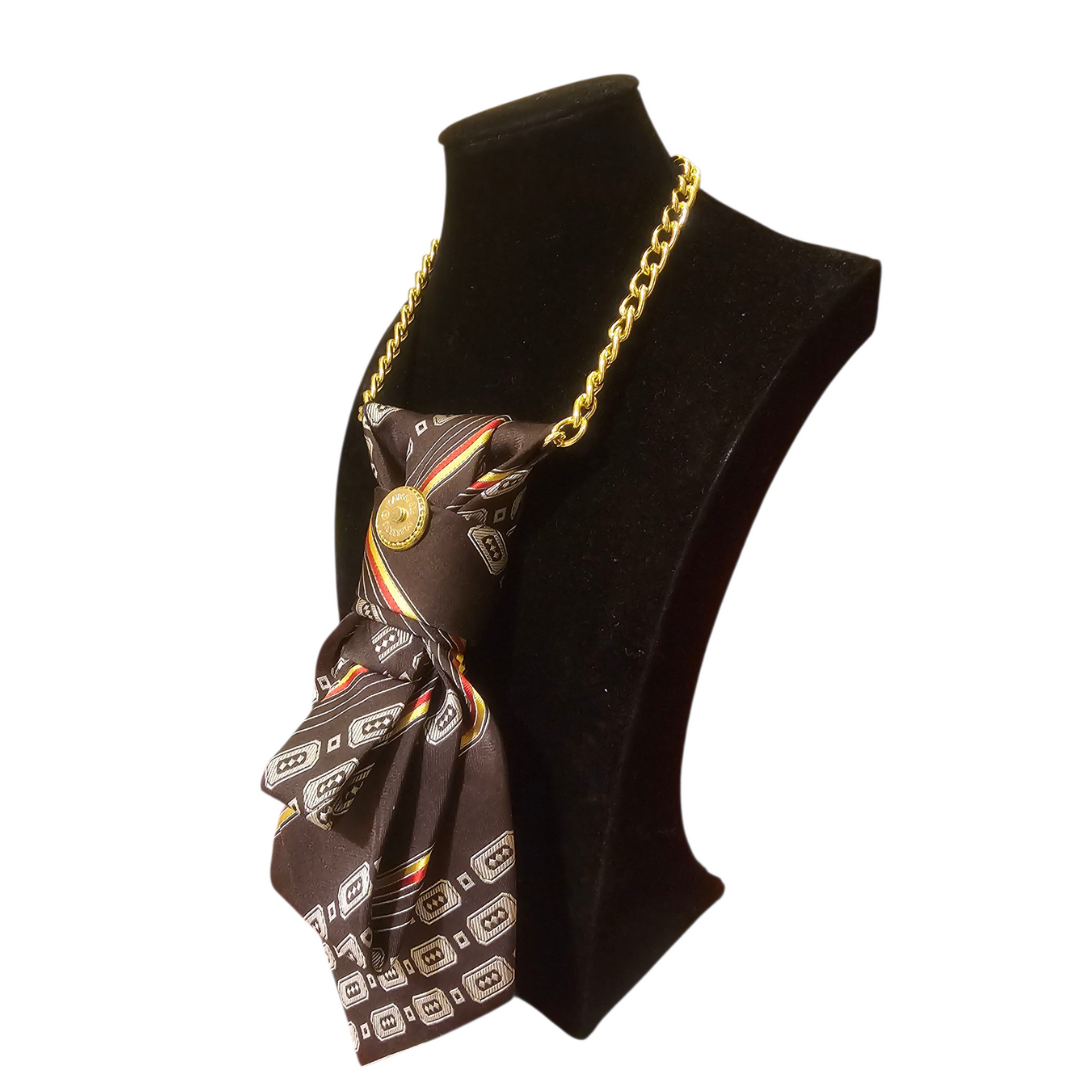 Brown patterned 4-in-1 Jeweled Tie draped on a gold chain displayed on a black bust