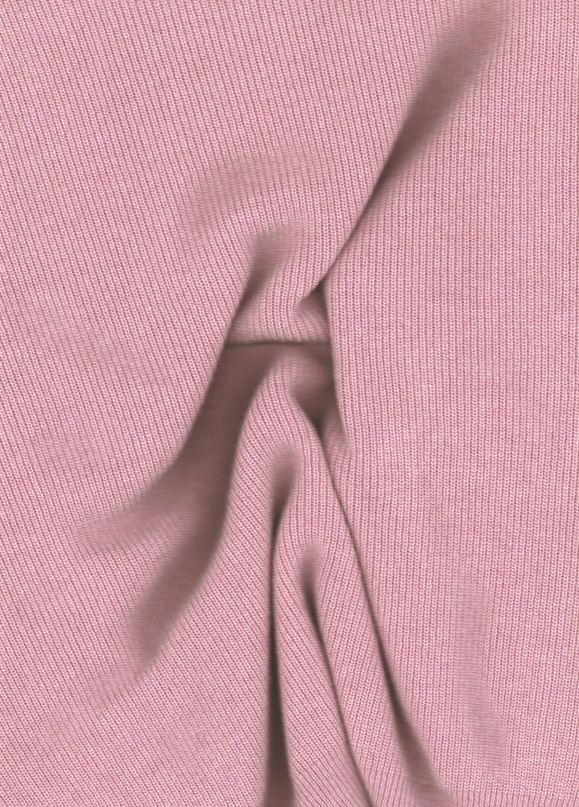 Close-up of soft pink ribbed knit fabric from a wool and cashmere mix high neck sweater