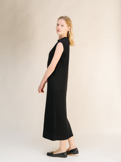 Side view of a black Wool & Cashmere Mix Sleeveless Cable Knit Dress with a ribbed hem and high neckline
