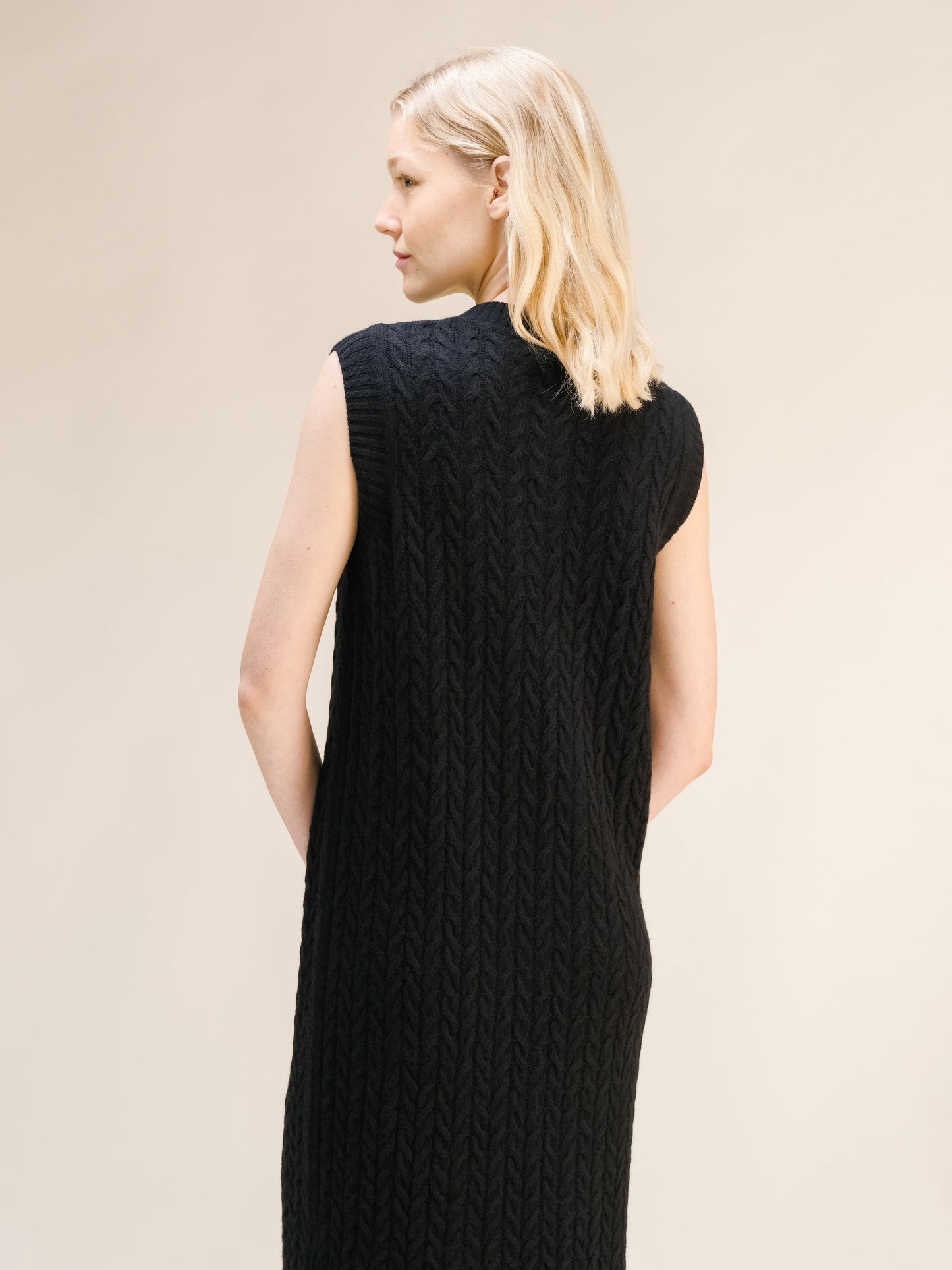 Black Wool & Cashmere Mix Sleeveless Cable Knit Dress featuring a textured cable pattern and a high neckline viewed from the back.