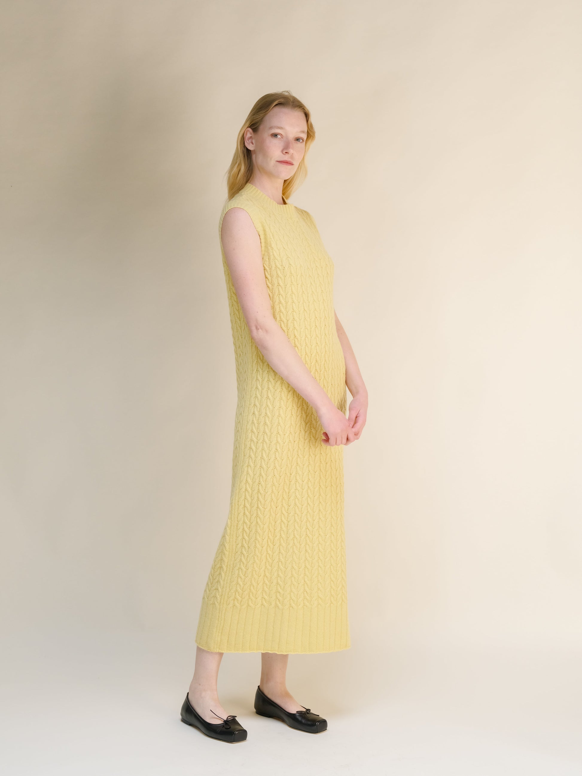 Wool & Cashmere Mix Sleeveless Cable Knit Dress in soft yellow with textured knit pattern and ribbed hem in a long midi length.